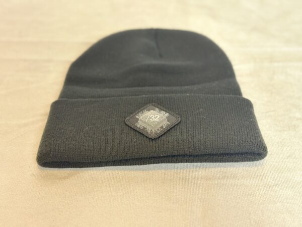 Image of the black “We Will Resist” rolled beanie by Slash-32 with a diamond-shaped patch featuring the /32 microchip symbol sewn in.