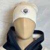 Image of white slouch style fitted beanie on mannequin with diamond-shaped white patch featuring microchip symbol and “/32” text, sewn onto front of hat.