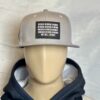 Image of mannequin wearing the Slash-32 9/50 Snapback hat, Grey "We Will Resist" cap with hoodie, showing the front patch with binary and “We Will Resist” text.