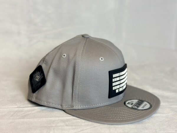 Side view image of the Slash-32 9/50 Snapback hat, Grey "We Will Resist" cap, showing both the front binary patch with text and the diamond-shaped /32 microchip patch on the side.
