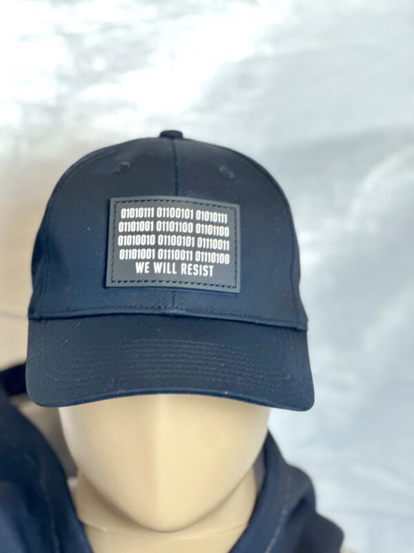 Image of mannequin wearing Slash-32 Ladies Snug Black "We Will Resist" Snapback Cap, showing binary code and “We Will Resist” on the front panel, with the microchip /32 patch on the side.