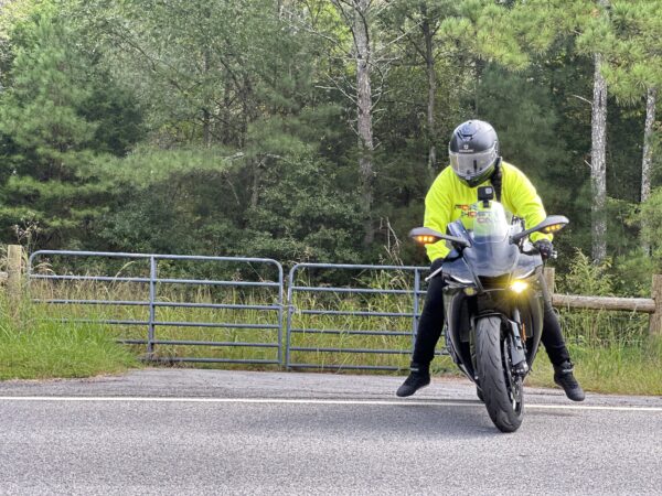 Image of a knøwn høst wearing the yellow FH0 – Knøwn H0st’s Binary Hoodie by Slash-32, actively driving a motorcycle, showing the custom binary signature on the hood.