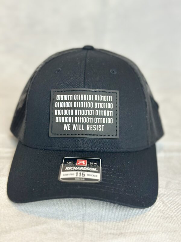 Image of Slash-32 Trucker Style Snapback hat - Black "We Will Resist" cap, front view showcasing the black rectangle patch with binary matrix and “We Will Resist” text.