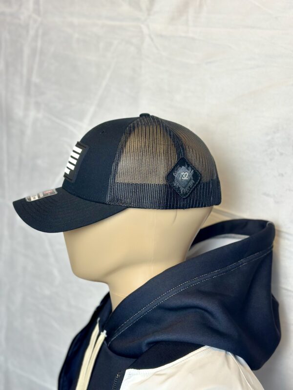 Image of Slash-32 Trucker Style Snapback hat - Black "We Will Resist" cap, side view showing the black diamond-shaped /32 microchip patch and partial view of the front binary patch.