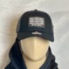 Image of Slash-32 Trucker Style Snapback hat - Black "We Will Resist" cap on mannequin, featuring a black rectangle patch with binary matrix and “We Will Resist” text on the front.