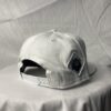 Side-back view image of Slash-32 9/50 Snapback hat, White showing the white diamond-shaped /32 microchip patch.