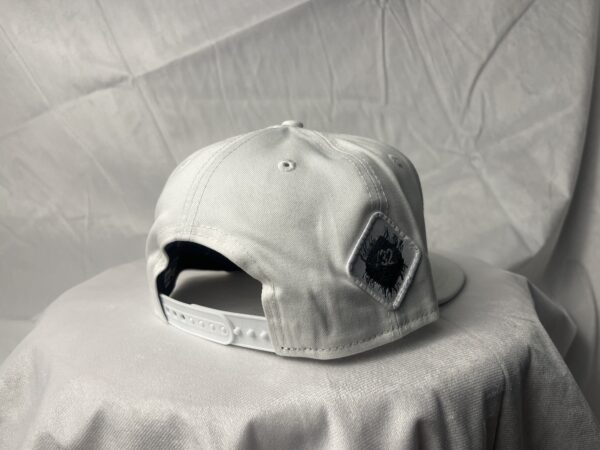 Side-back view image of Slash-32 9/50 Snapback hat, White showing the white diamond-shaped /32 microchip patch.