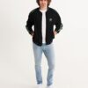 Front view of male model wearing the men’s ‘We Will Fight’ Black Label jacket from Slash-32’s Preamble Collection, hands in pockets. A streetwear piece symbolizing defiance and digital freedom.