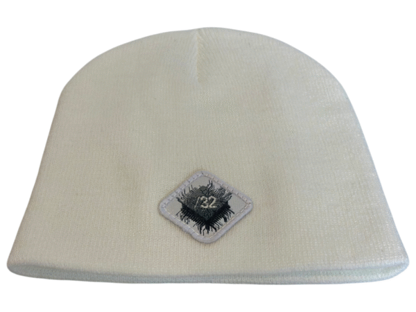 Image of white skull cap style fitted beanie with diamond-shaped white patch featuring microchip symbol and “/32” text, sewn onto front of hat.