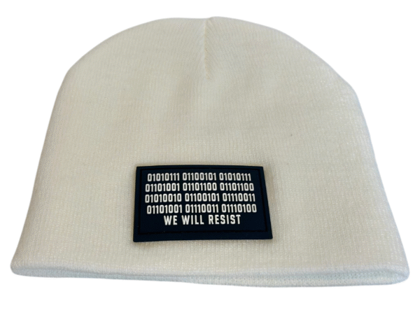 Image of white skull cap style fitted beanie with rectangular black patch featuring binary code above “We Will Resist” text, sewn onto front of hat.