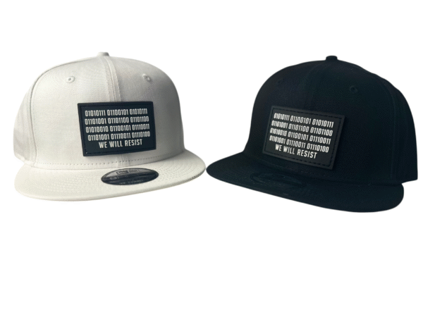 Front view image showing two Slash-32 snapbacks, black and white, both with black rectangular patch with binary and “We Will Resist” text.