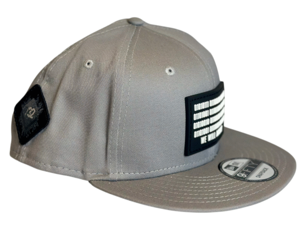 Side view image of the Slash-32 9/50 Snapback hat, Grey "We Will Resist" cap, showing both the front binary patch with text and the diamond-shaped /32 microchip patch on the side.