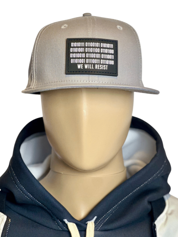 Image of mannequin wearing the Slash-32 9/50 Snapback hat, Grey "We Will Resist" cap with hoodie, showing the front patch with binary and “We Will Resist” text.