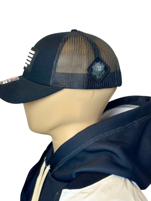 Image of Slash-32 Trucker Style Snapback hat - Black "We Will Resist" cap, side view showing the black diamond-shaped /32 microchip patch and partial view of the front binary patch.