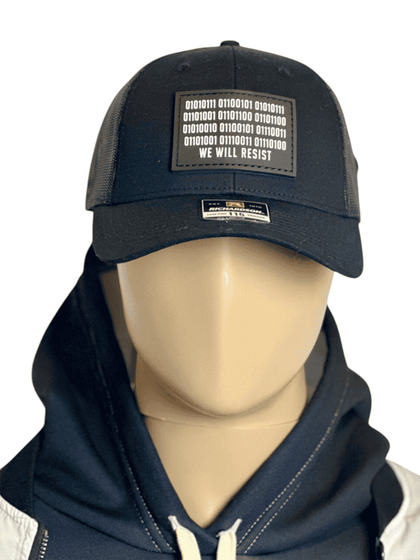 Image of Slash-32 Trucker Style Snapback hat - Black "We Will Resist" cap on mannequin, featuring a black rectangle patch with binary matrix and “We Will Resist” text on the front.